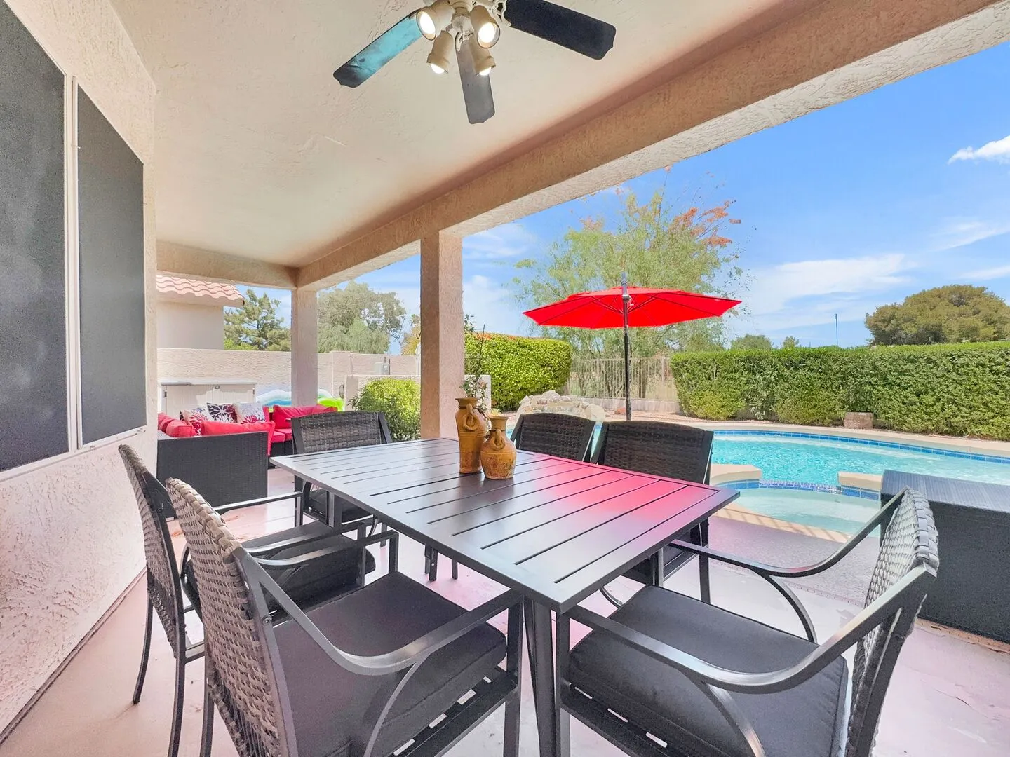 Covered back patio with an outdoor dining table for six and a ceiling fan, looking out to the pool